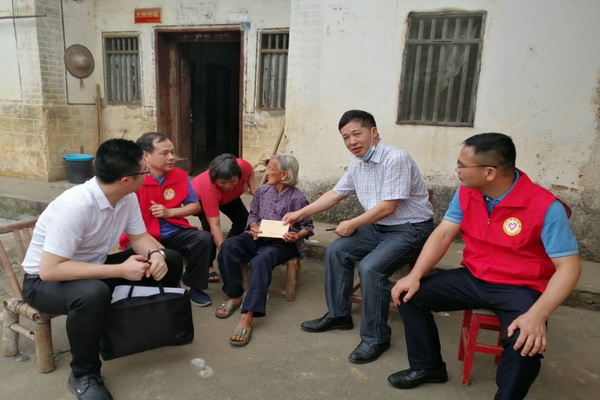 图为志愿者为贫困残疾人送上慰问金.jpg